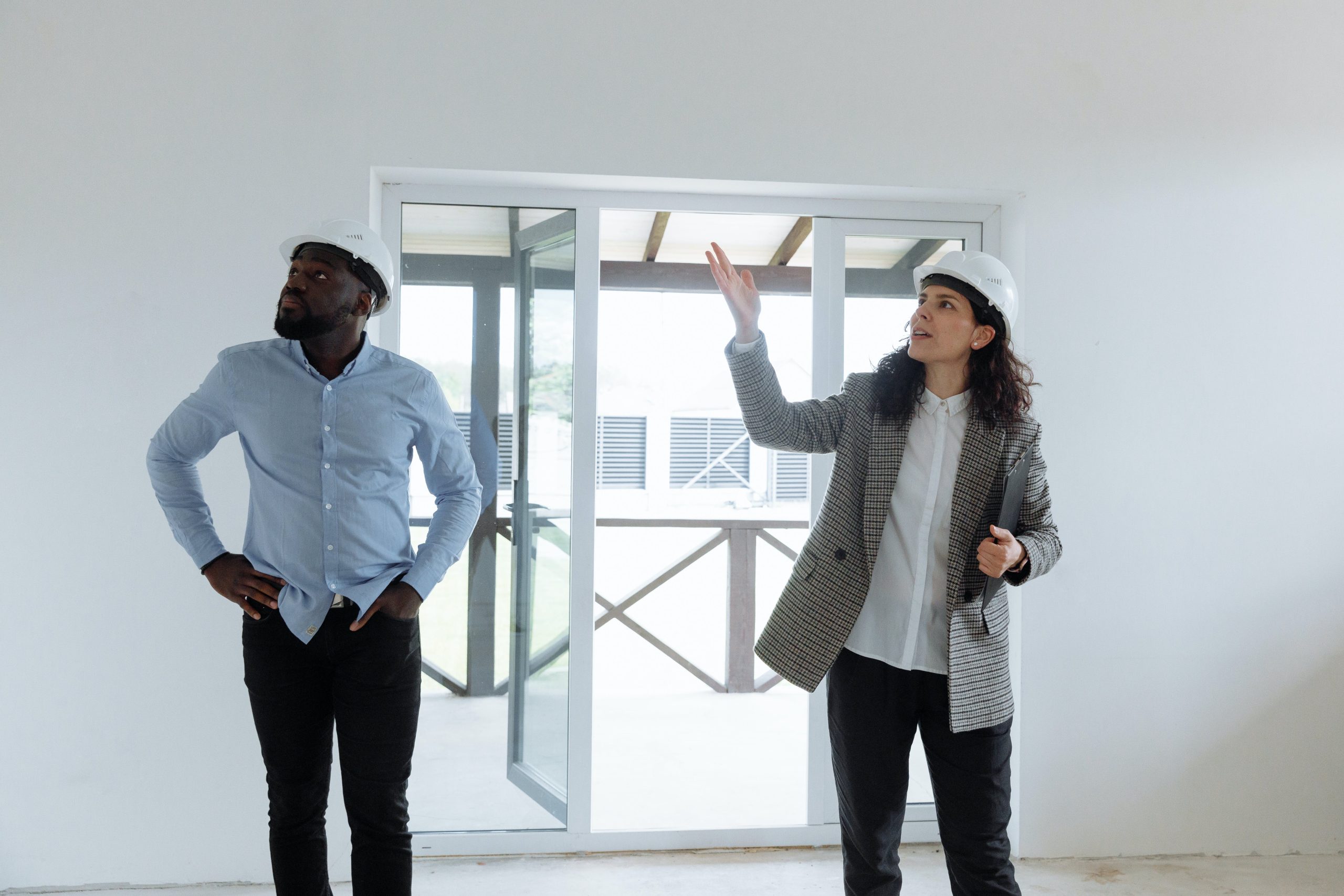 a man and a woman wearing white hard hats inside of a room under construction